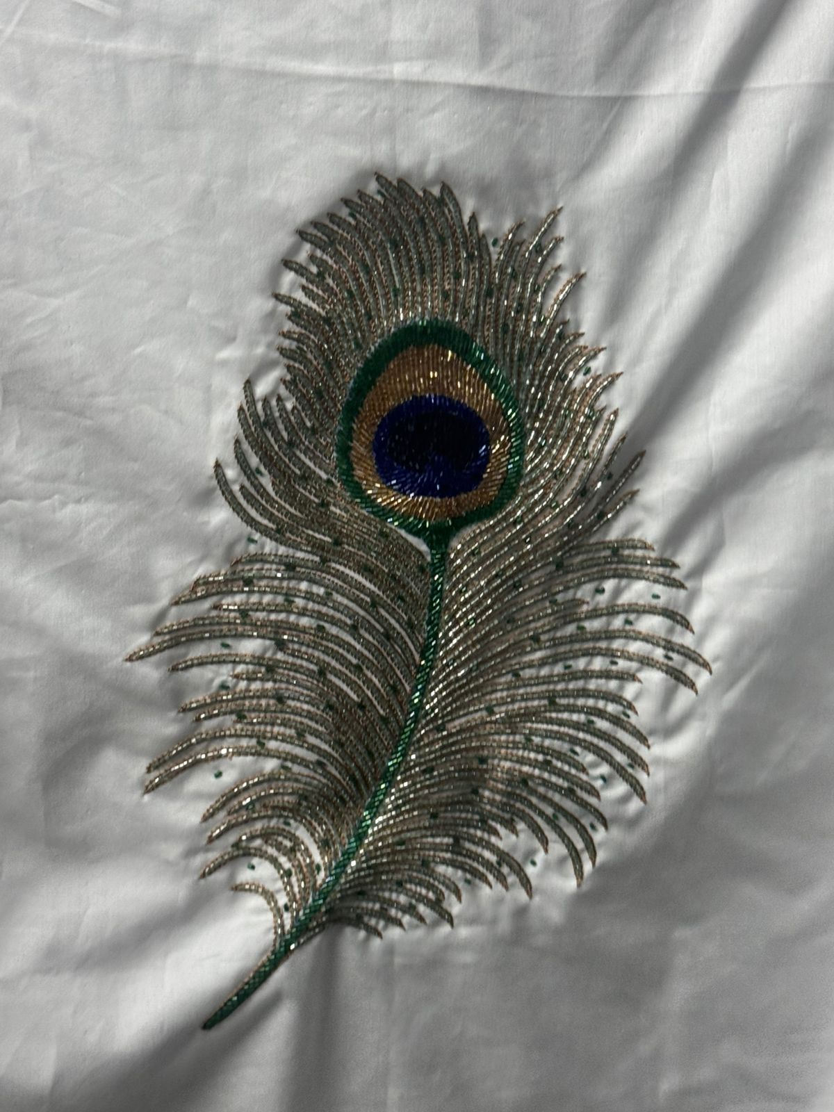 Hand beadwork peacock feather in gold and green on white shirting